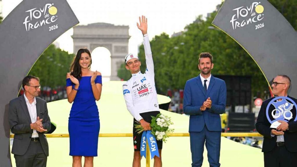 Isaac del Toro en el podio del Tour de Francia 2026, celebrando su tercer lugar junto a otros presentadores y el Arco del Triunfo de fondo.