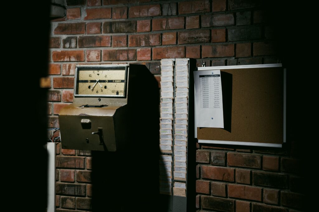Reloj checador antiguo junto a una pared de ladrillos, simbolizando el control del tiempo laboral en el contexto de la