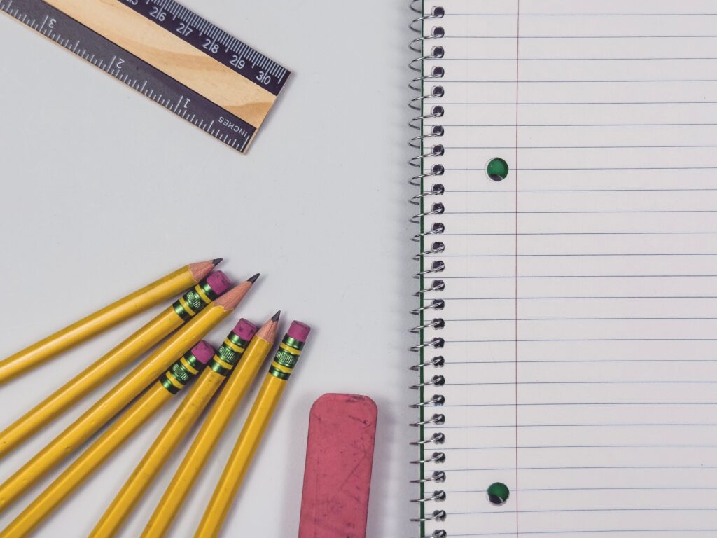 Lápices amarillos, una regla y un cuaderno en blanco sobre una mesa, elementos esenciales para el regreso a clases en México.