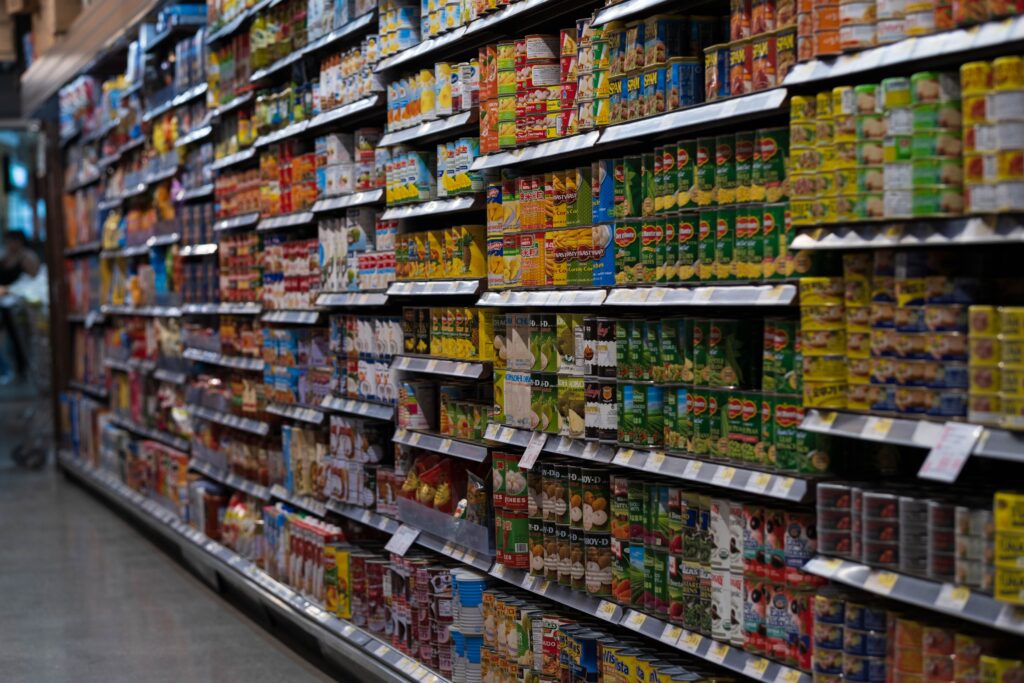 Estantes de supermercado repletos de productos enlatados y envasados, reflejando la variedad de opciones alimenticias.