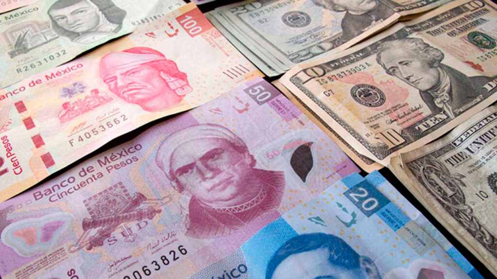 Billetes de pesos mexicanos y dólares estadounidenses sobre una superficie, representando la fluctuación del tipo de cambio entre ambas monedas.