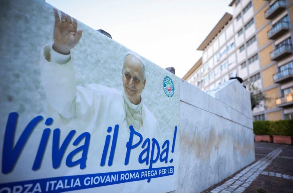 Pancarta con la imagen del papa León XIV, que dice "Viva il Papa!", colocada frente a un edificio en Roma, en apoyo a su recuperación.