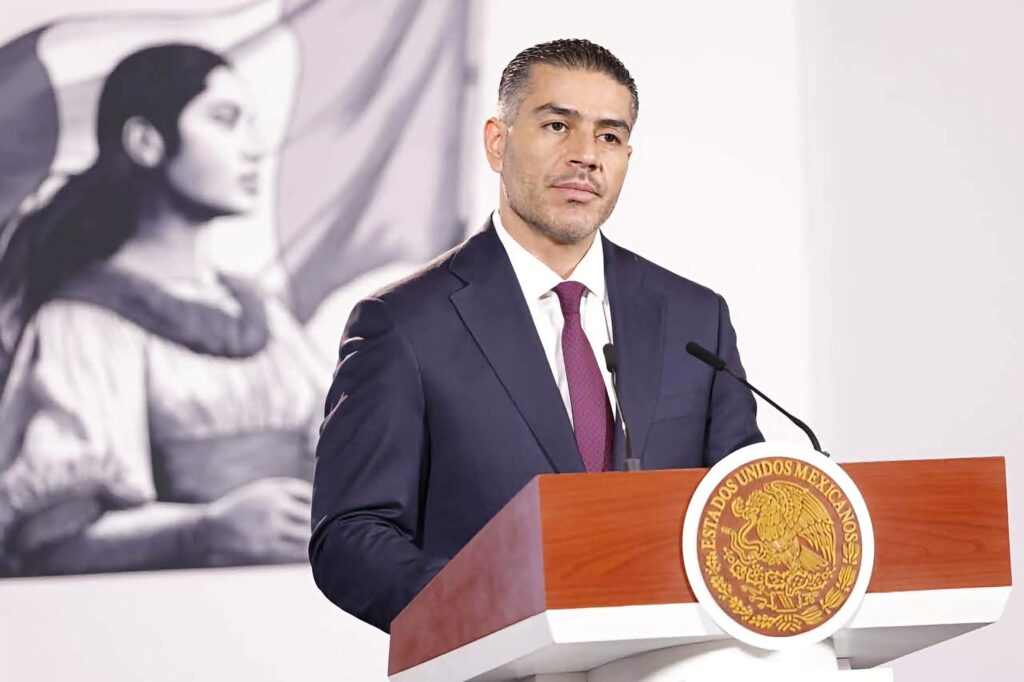 Omar García Harfuch, secretario de Seguridad, presenta avances en seguridad en México, con un mural de fondo que simboliza la cultura nacional.