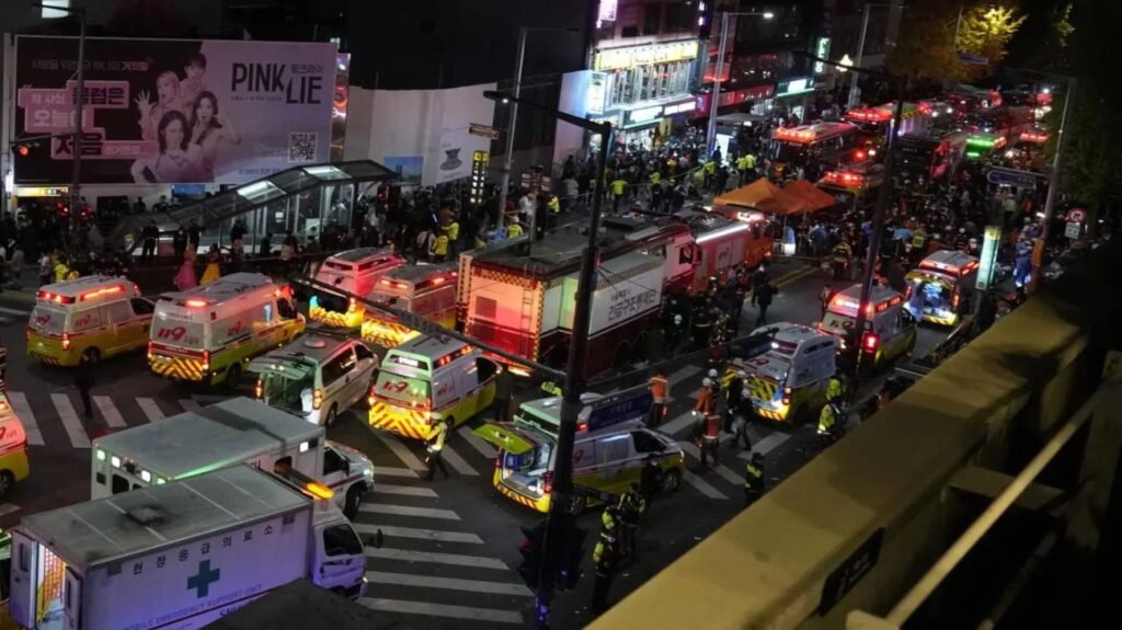 Multitud de ambulancias y vehículos de emergencia en Itaewon tras la tragedia, con personas y luces parpadeantes en la escena.